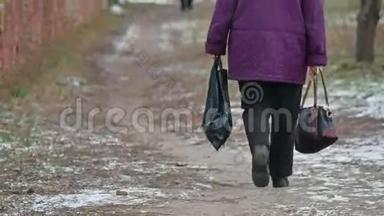 老妇人一瘸一拐地走在街上，背着一个袋子和一包深秋的<strong>户外用品</strong>